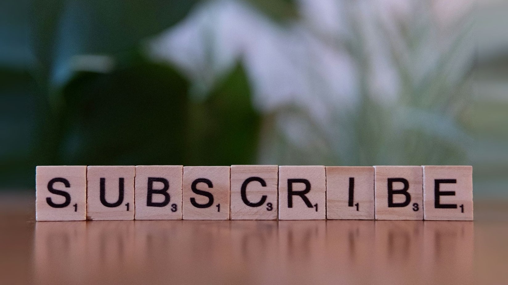 Letter tiles spelling the word subscribe on a wooden table