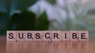 Letter tiles spelling the word subscribe on a wooden table